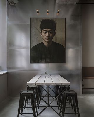 Looking along a table with stools either side, towards a framed portrait