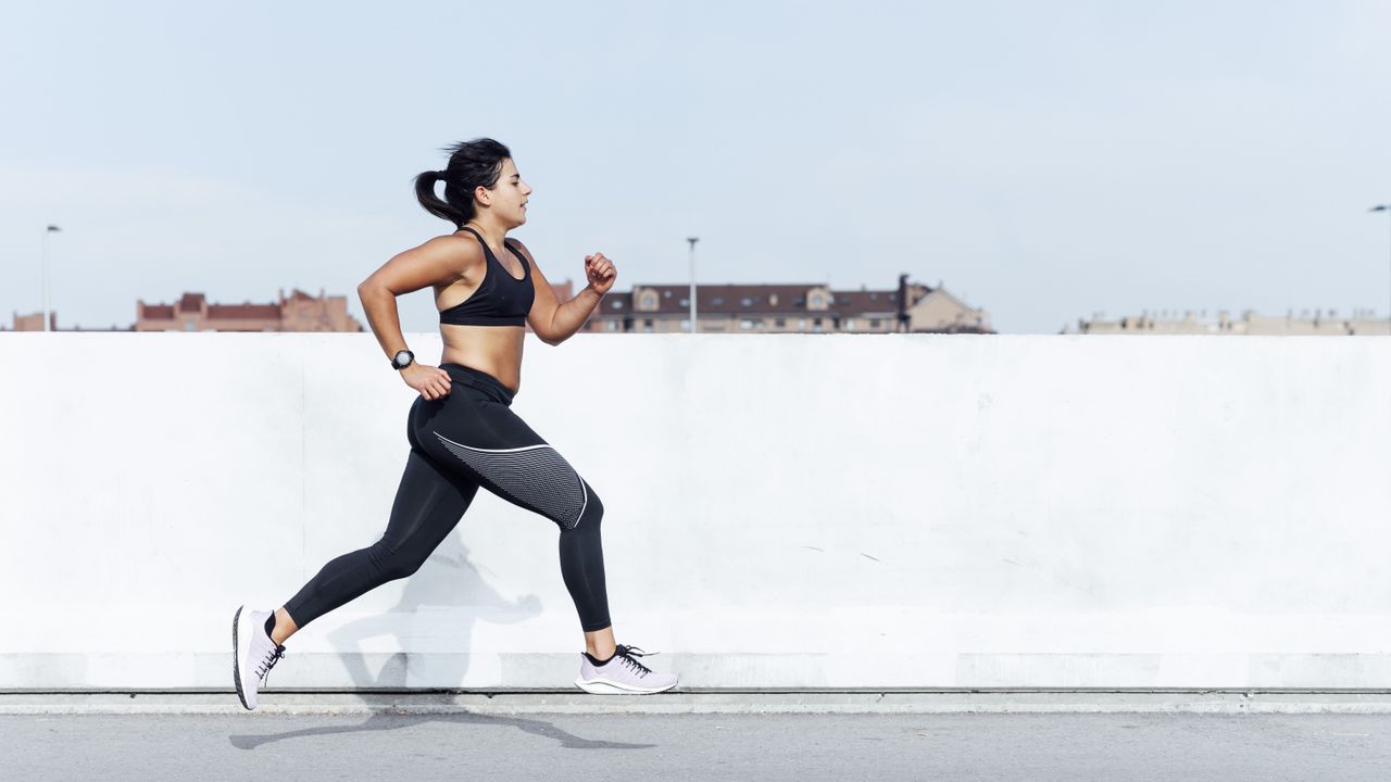 woman running outside by white wall 