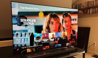 Bästa 65-tums TV: En Sony XR A80K OLED TV står på en svart liten TV-bänk och visar startsidan för Stranger Things med ett gäng andra serier i en meny nedanför.