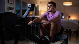 Young man on best rowing machine in home