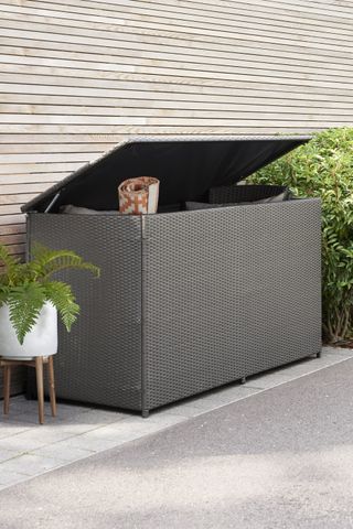 black textured storage box on a modern patio with a planter