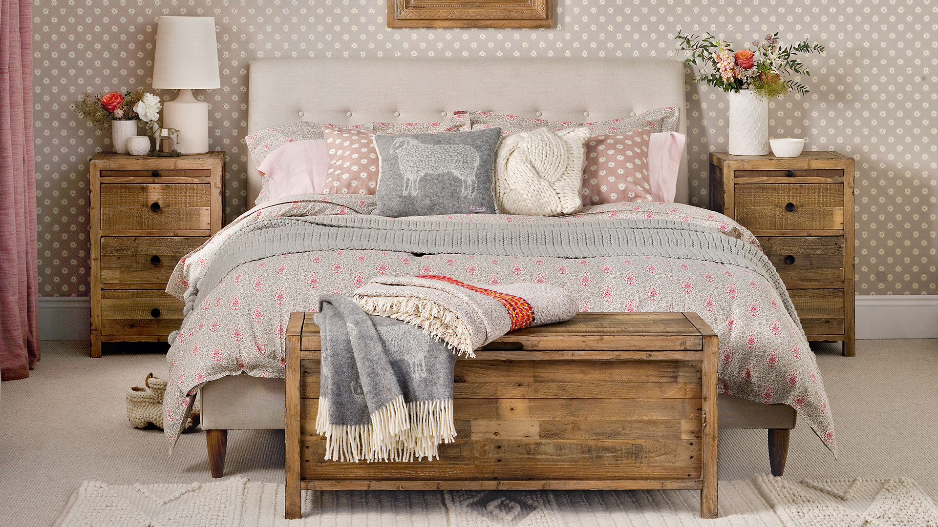Neutral bedroom with beige linen upholstered bed, wooden beside tables and wooden storage chest at the foot of the bed
