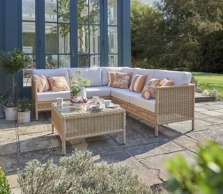 rattan garden furniture on stone paver patio outside blue conservatory