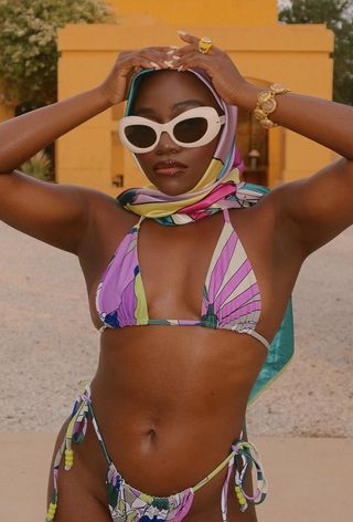 a photo of a woman's vacation outfit with a printed bikini, scarf over the head, and white sunglasses