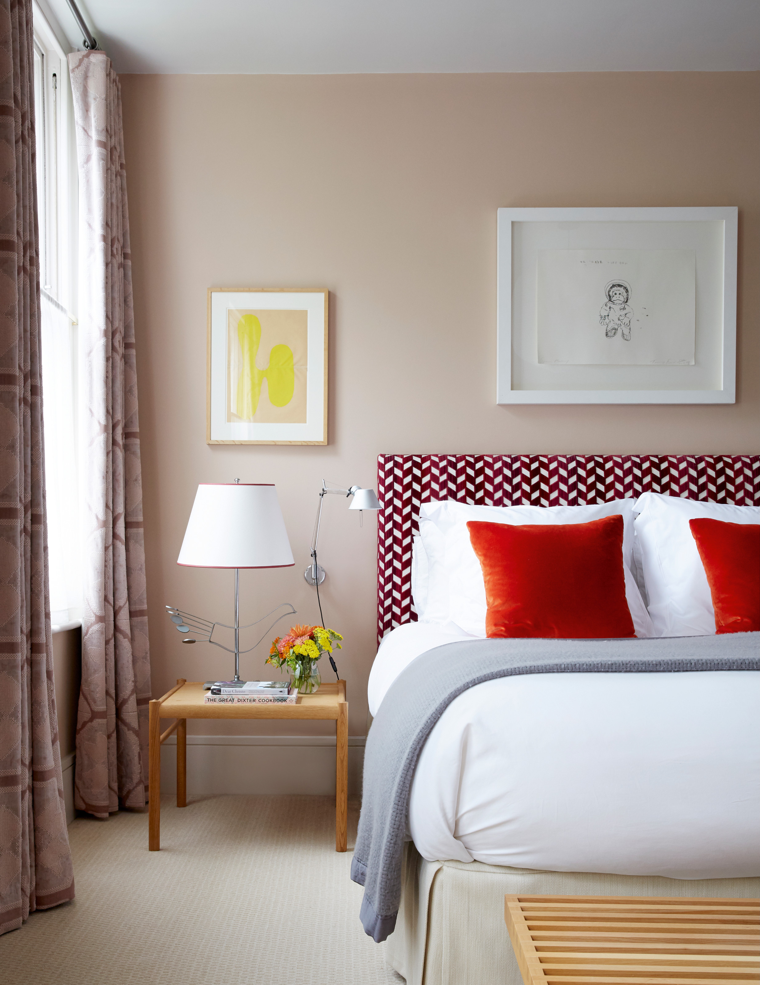 Peach bedroom with red and white patterned headboard and wood side table