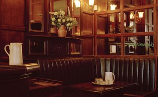 Restaurant with leather banquettes and antique lighting at Marksman, London, UK