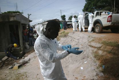 MONROVIA, LIBERIA - AUGUST 14:Aburial team prepares to collect the dead body of a woman suspected of dying of the Ebola virus on August 14, 2014 in Monrovia, Liberia. Teams of undertakers wea