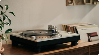 Technics turntable with Ortofon Quintet Blue cartridge on wooden console with records in background