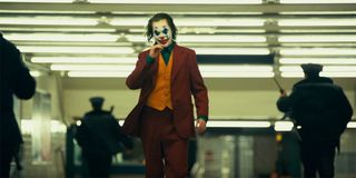 Joker nonchalantly walking away from whatever terror he caused