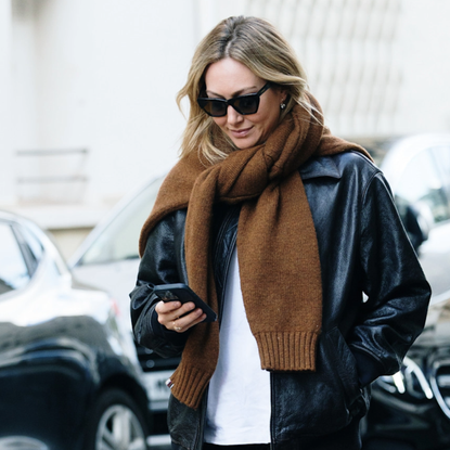 woman wearing a black leather jacket and brown scarf. 