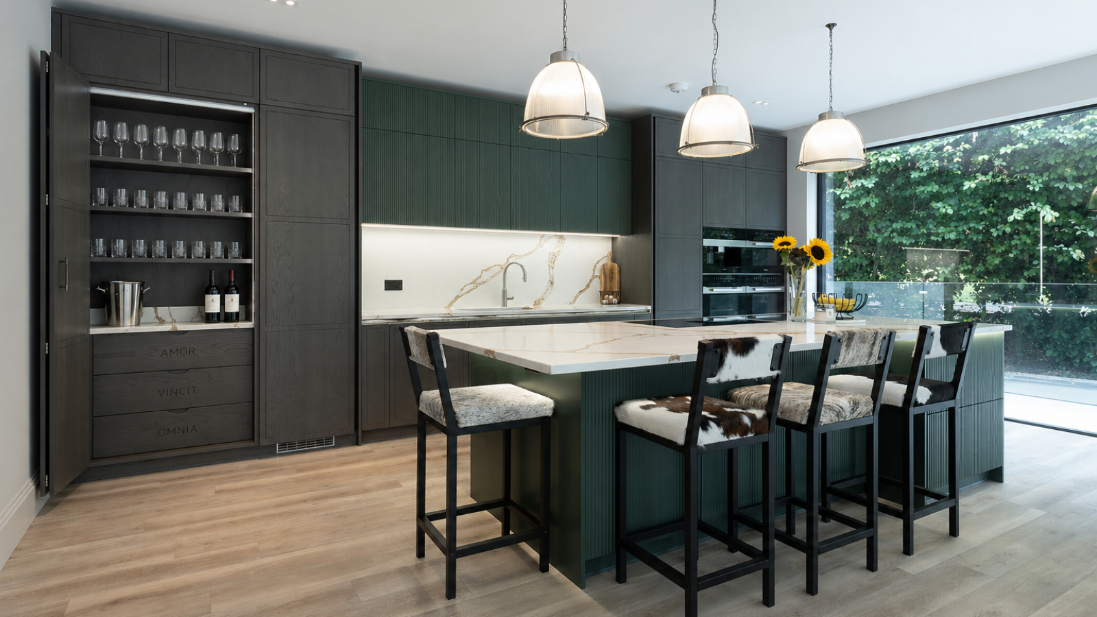 kitchen with one set of cupboards open housing glasses and bar items with large kitchen island with seats in centre of room