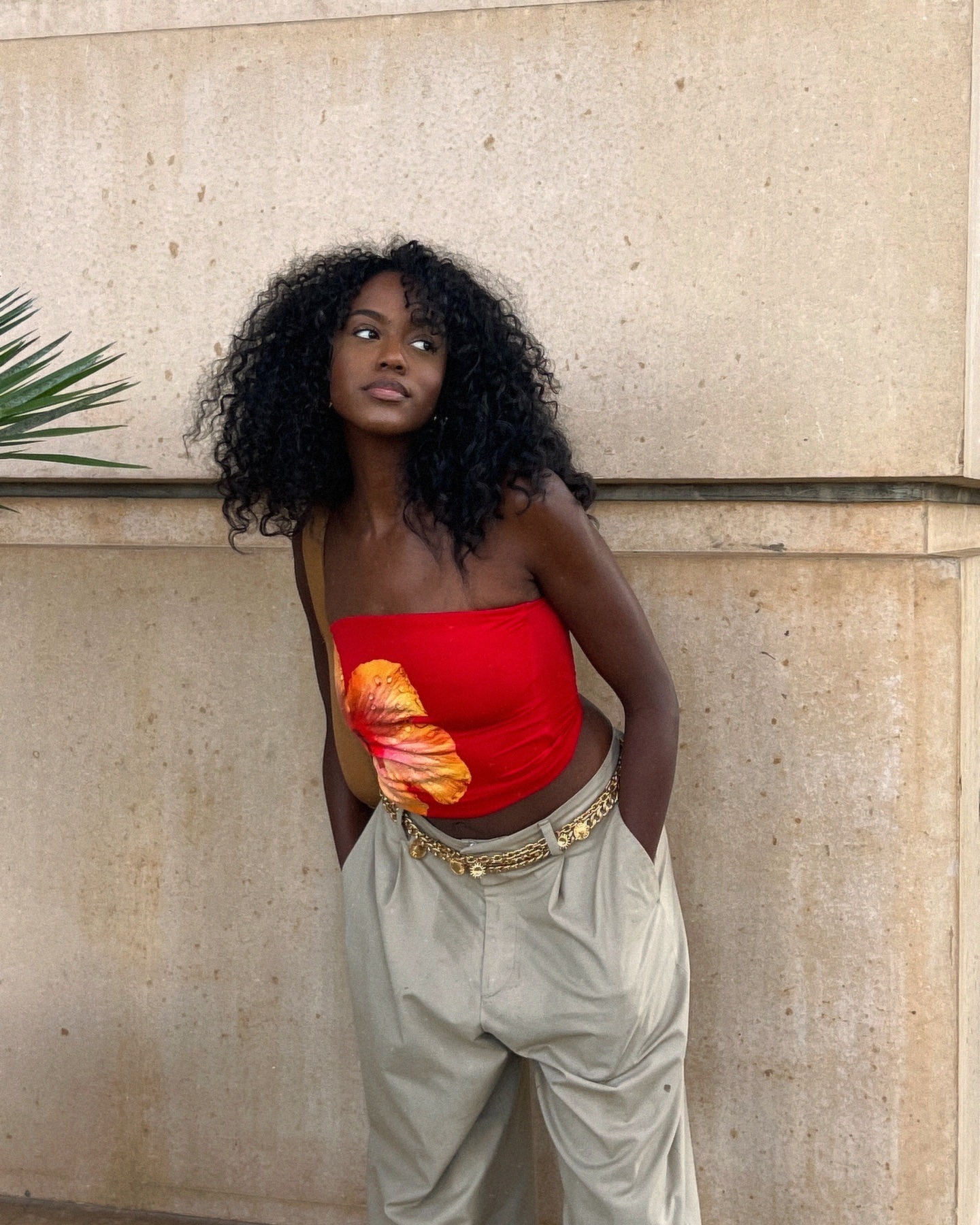 A woman leaning on a wall with curly hair.