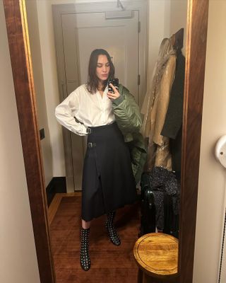 Alexa Chung styles a pleated skirt and a white shirt with studded boots
