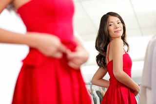 woman wearing red dress and looking in the mirror.