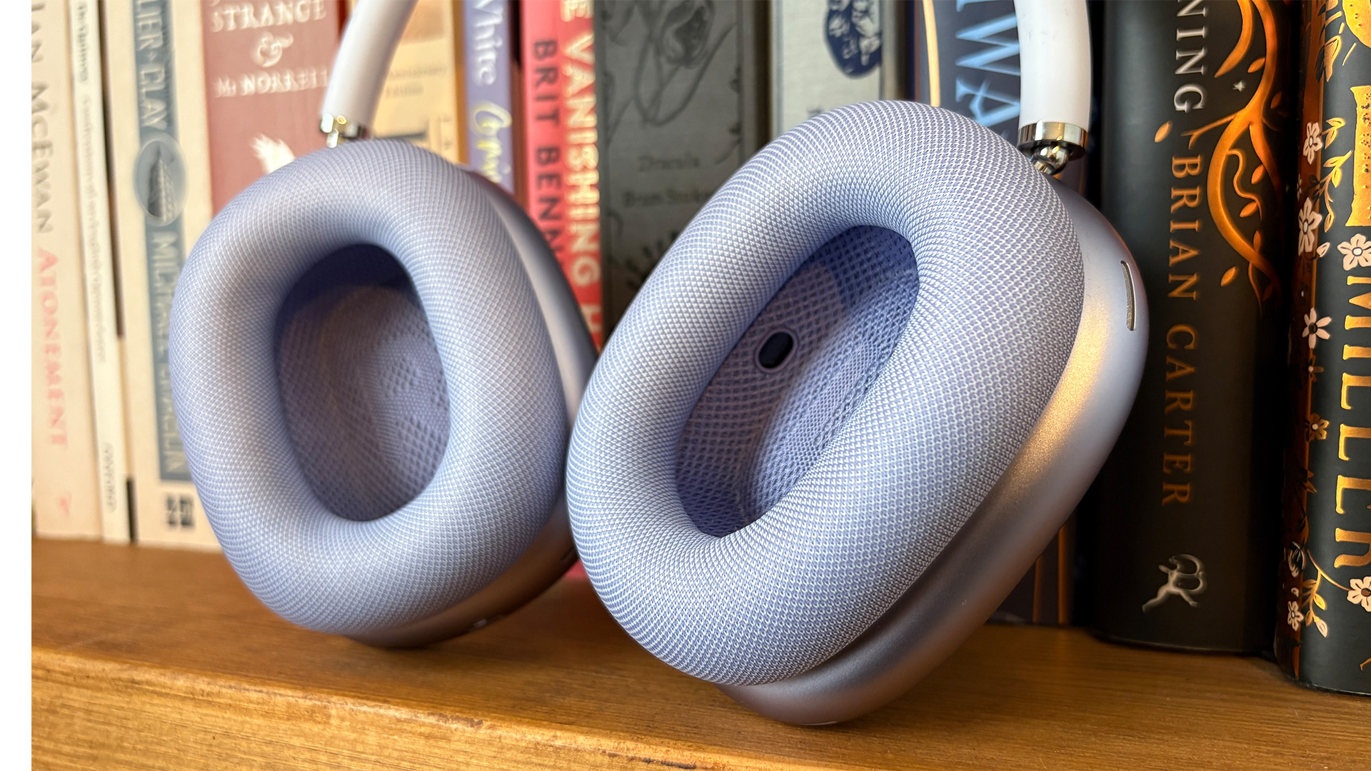 Apple AirPods Max 2 over-ear headphones on bookshelf close up on earcups