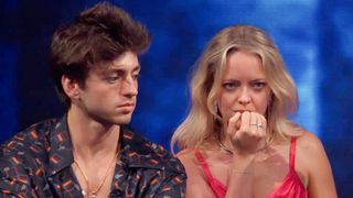 Drew and Melody during the Disco competition in Big Brother Season 28. He's wearing a colorful shirt with an open chested look. She's wearing a pink top and is biting her nails.