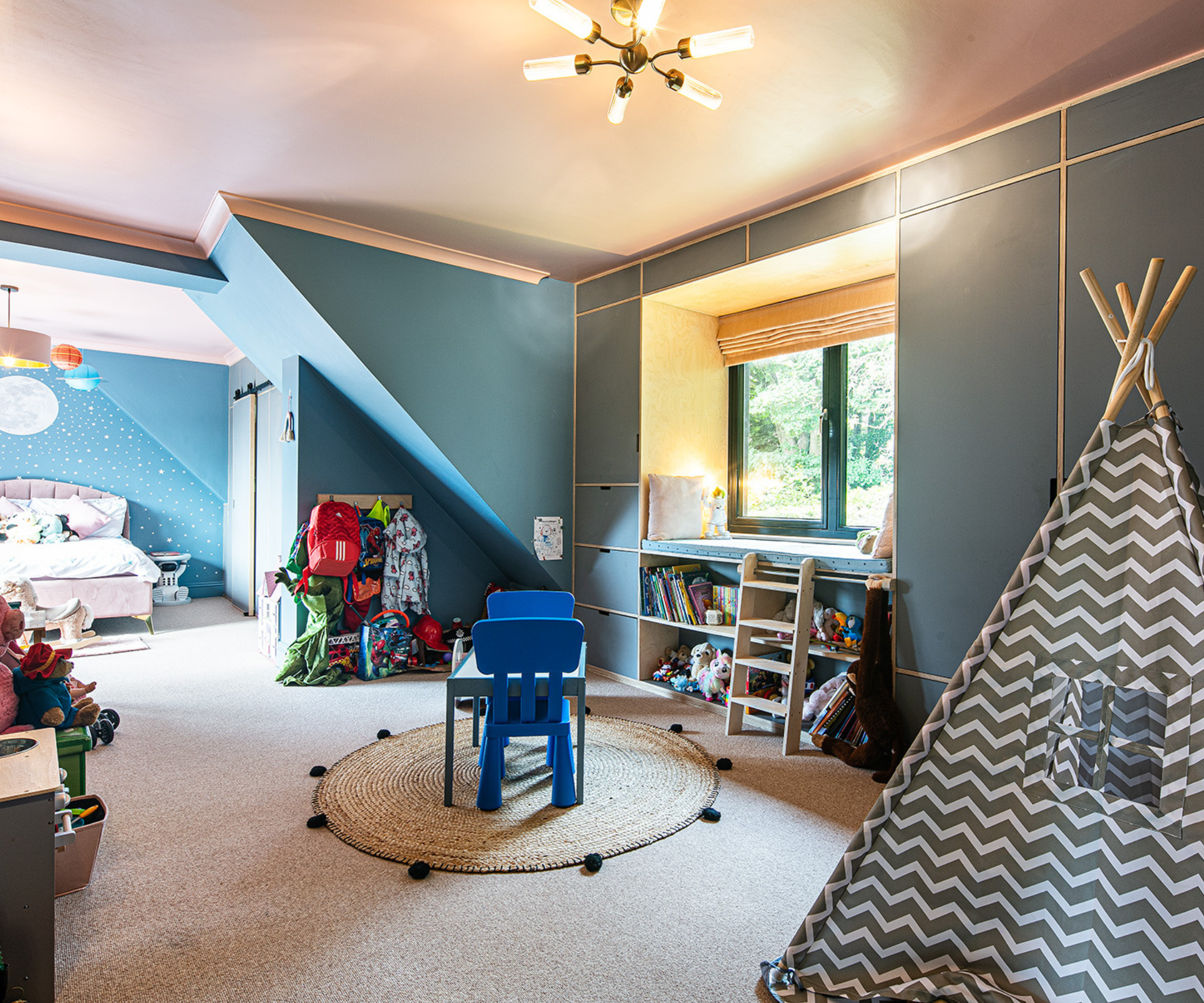 Childrens' playroom with window seat, teepee, and toys shelves