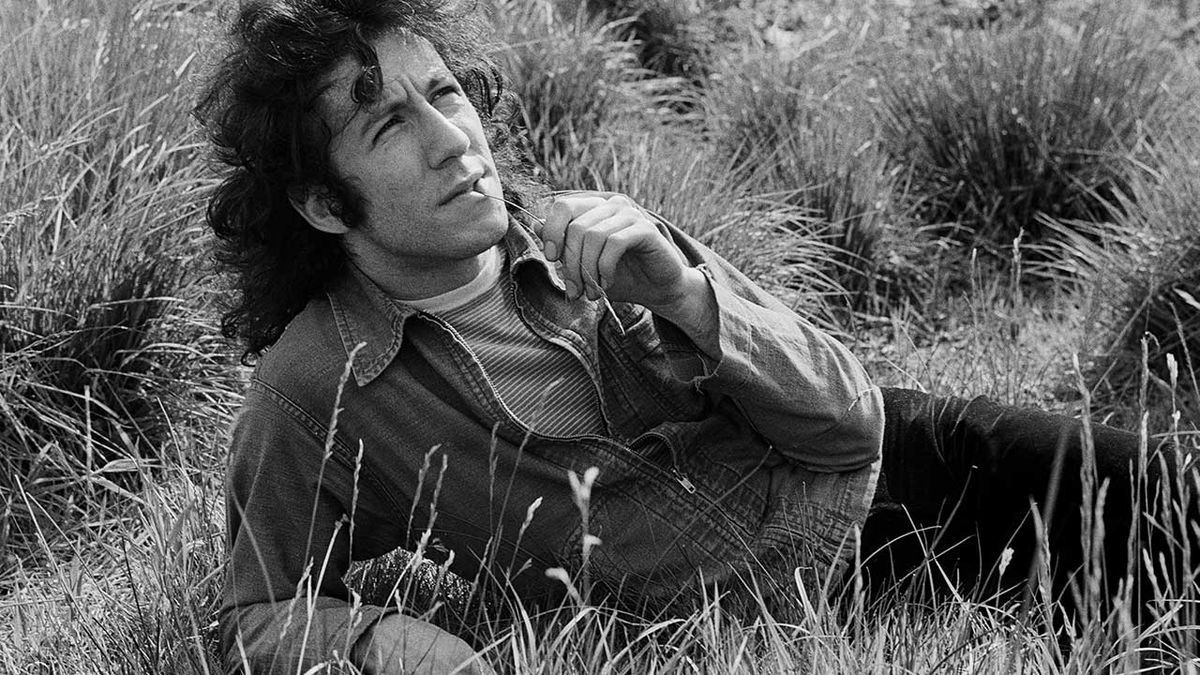 Peter Green relaxed in a field, chewing grass