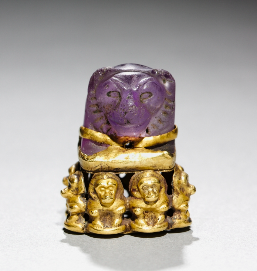a purple amethyst carved into a lion's head set atop a gold base of baboons