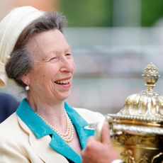 Princess Anne laughing and holding a gold trophy