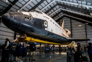 space shuttle endeavour in a museum hangar with people milling around it