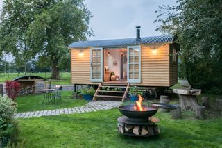 traditional shepherd's hut in a large garden with a fire pit and seating area outdoors