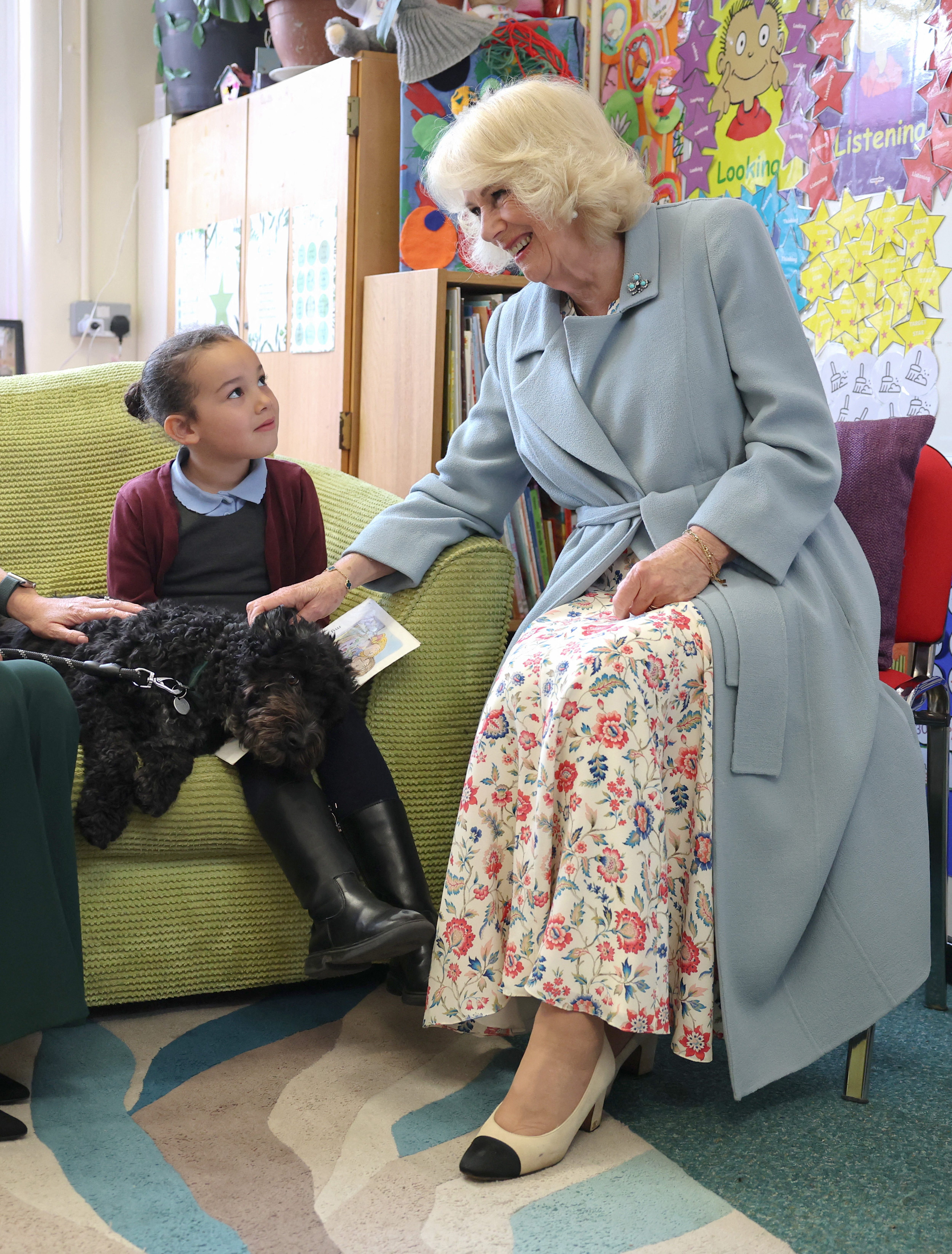 Queen Camilla petting a dog on a little girl's lap