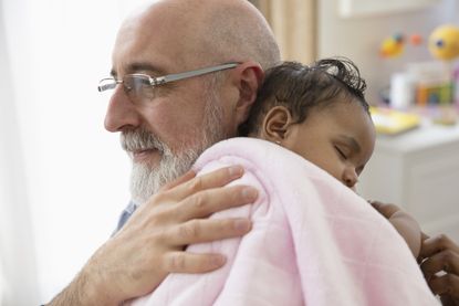 A grandfather holds his baby granddaughter in a tender moment.
