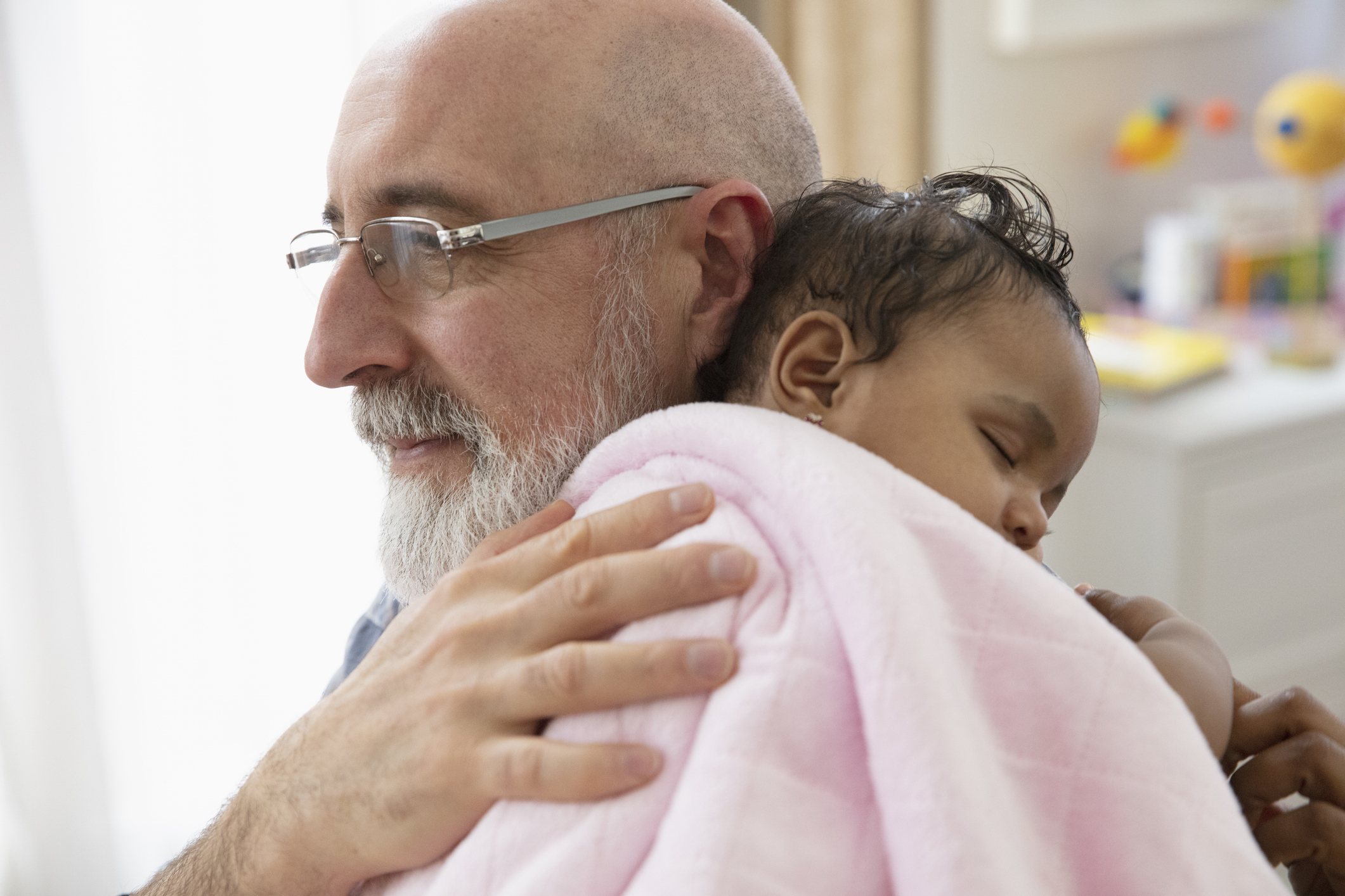A grandfather holds his baby granddaughter in a tender moment.