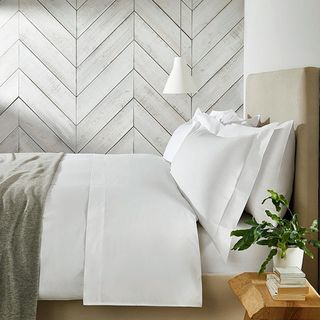 bed with white bedding and neutral throw and headboard