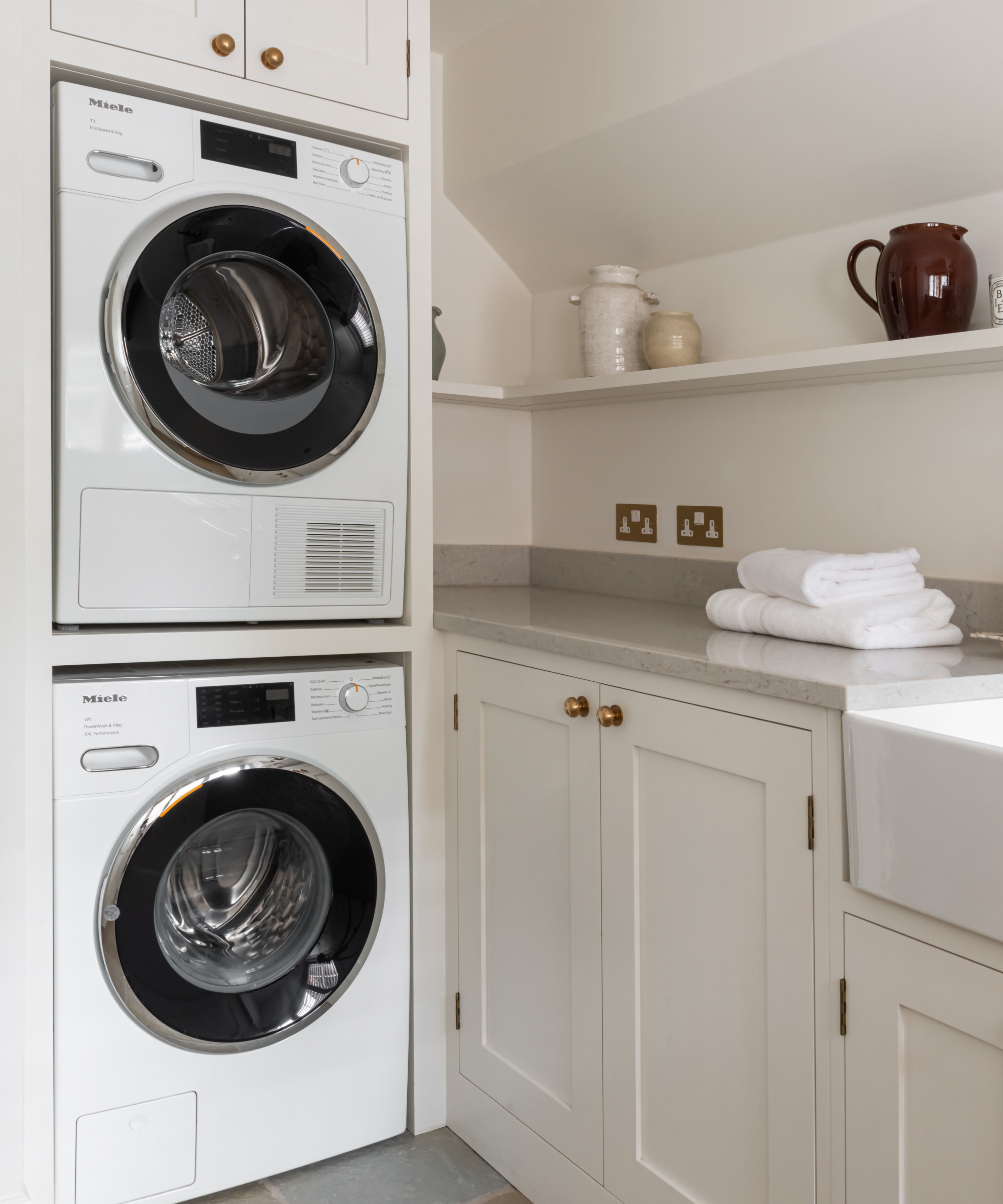 Utility corner with stacked washing machine and tumble dryer and cream cabinets