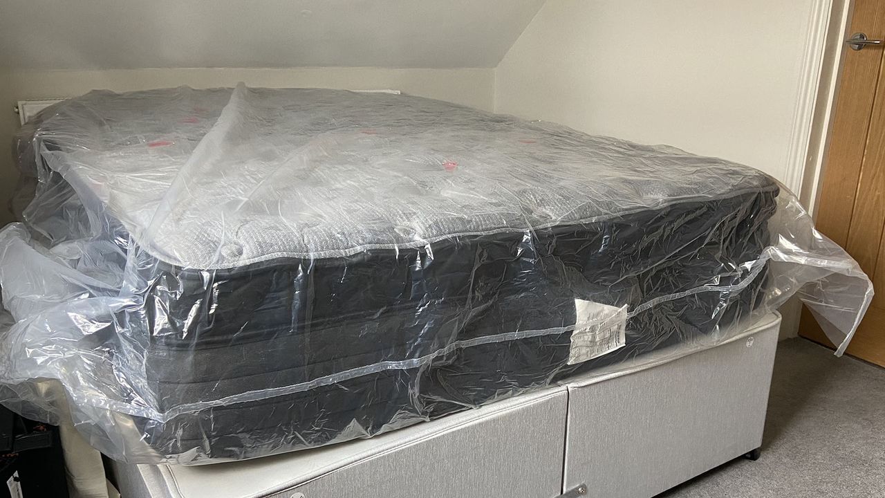 Zoma Boost mattress wrapped in plastic on a bedframe
