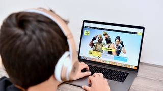 a child with headphones gaming on a macbook