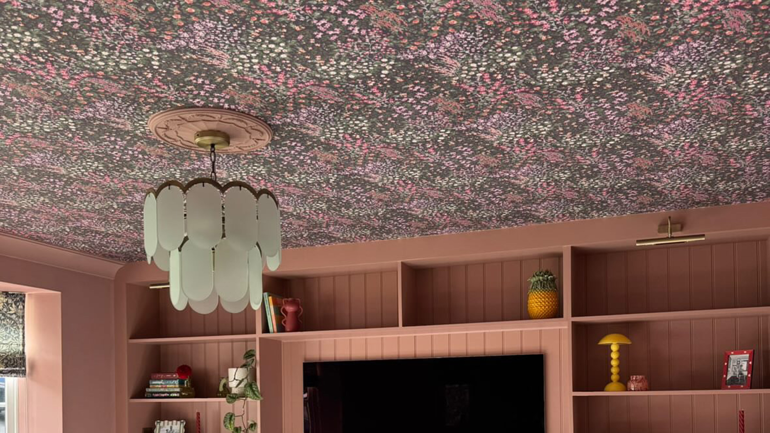 living room with pink joinery and wallpaper on the ceiling