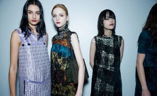 Models wearing a lilac dress, colorful orange, blue and yellow lace-covered dress with an olive leather bag, and blue and black dresses with lace trimming, from the Bottega Veneta A/W 2015.