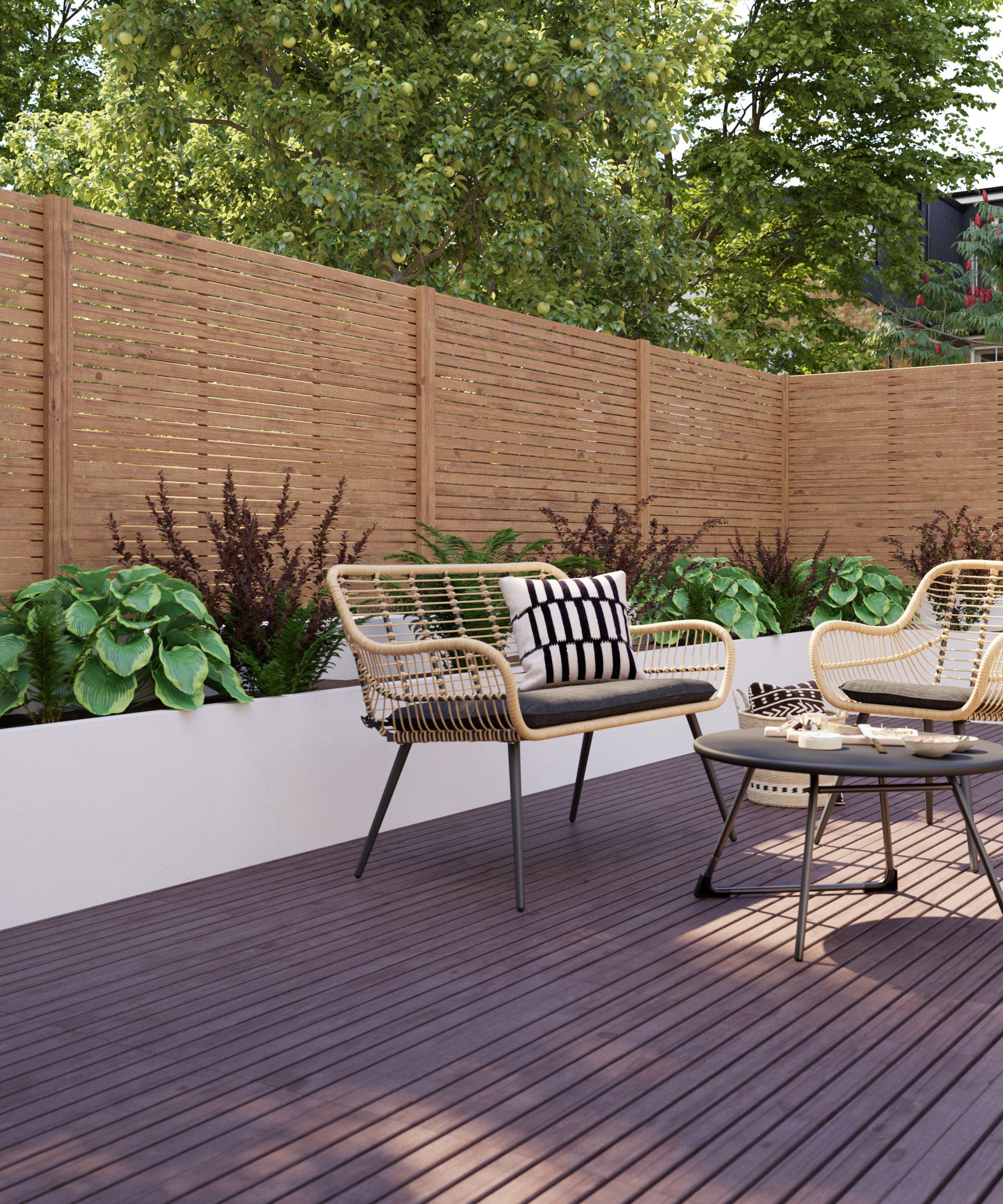 Dark decking, rattan chairs with cushions round black table, raised planters, slatted wood fence, trees behind.