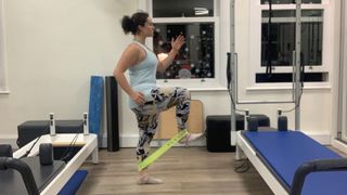 Person performing standing banded hip flexion