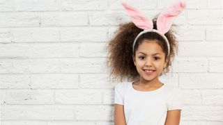 Image of a young girl with bunny ears on infront of a white wall