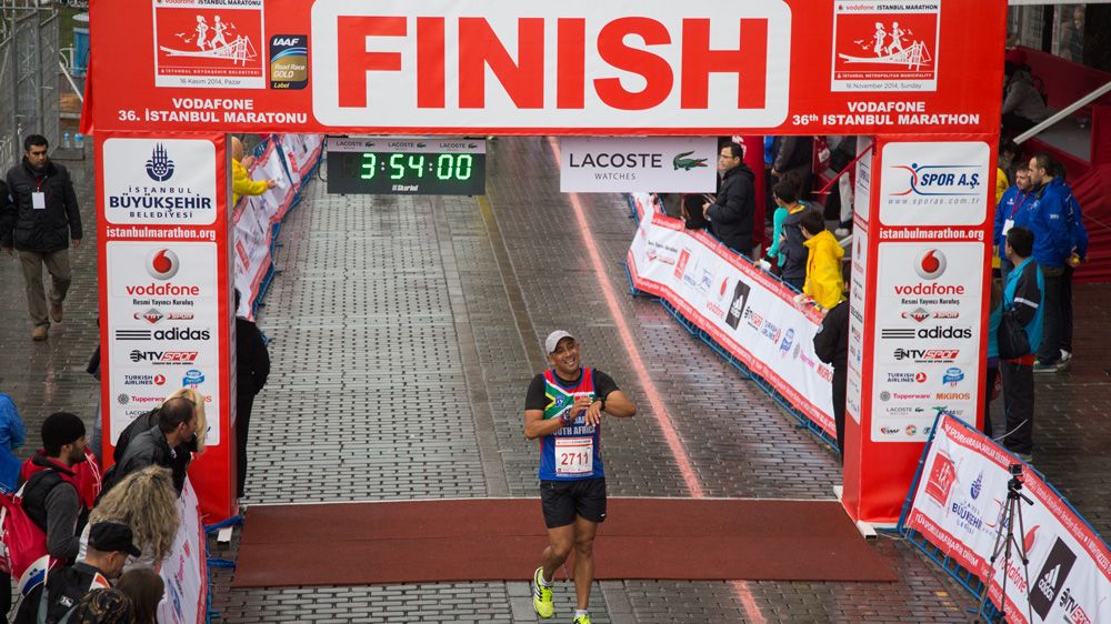 Man crosses the finish line at the Istanbul Marathon in under four hours, the display on the gantry reads three hours 54 minutes