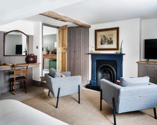 bedroom with fireplace, gray mid century style chairs, wardrobe, mirror and natural rug