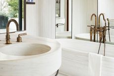 A bathroom with white walls, white bathtub and white vanity