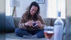 A sad woman sits on her couch after a breakup