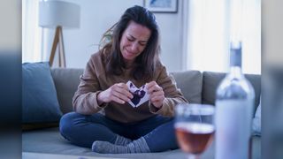 A sad woman sits on her couch after a breakup