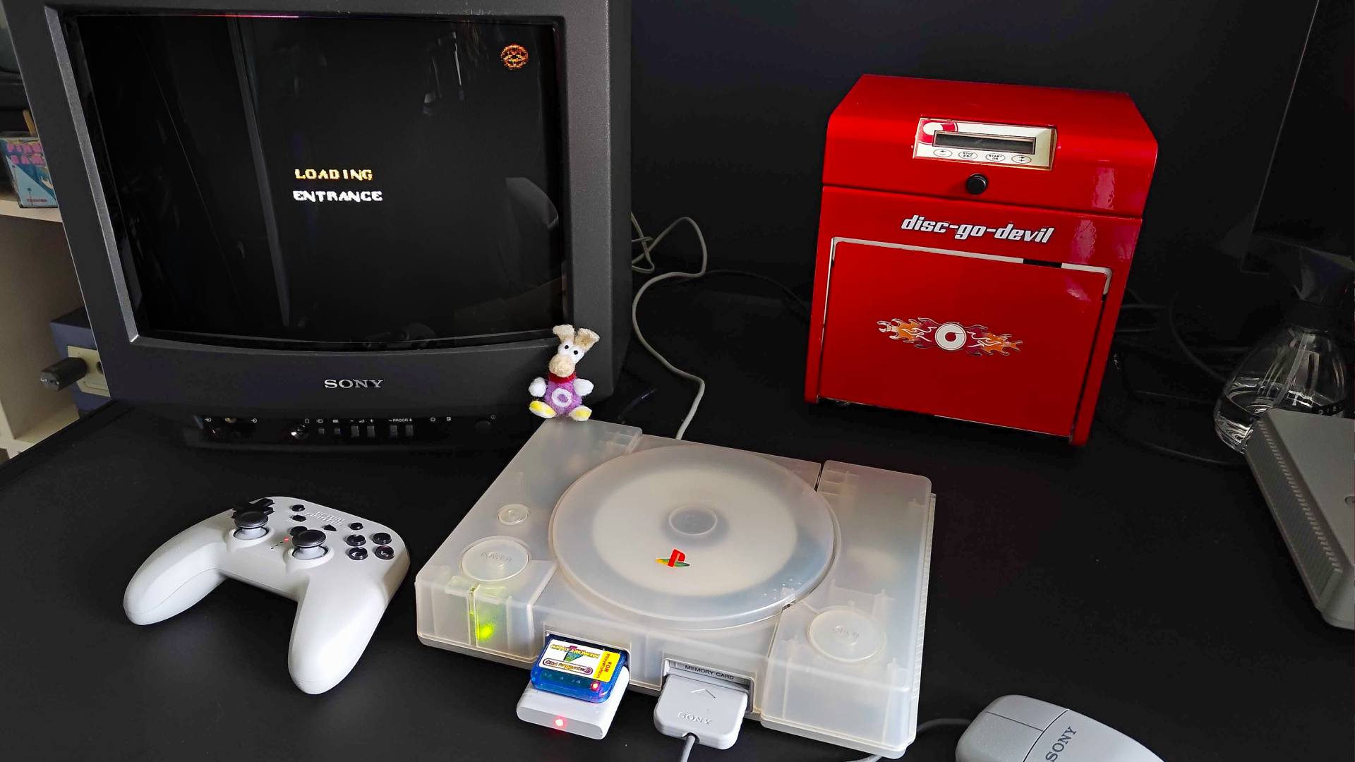 Transparent PS1 connected to Sony Trinitron CRT TV with Quake load screen displayed.