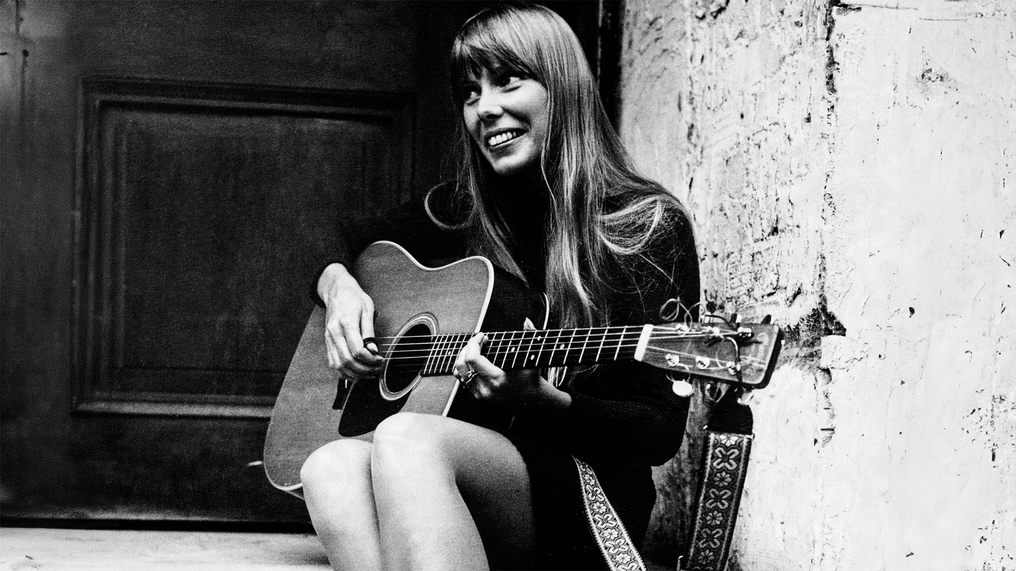 (Original Caption) A singer called Joni. Joni Mitchell, Canadian singer-songwriter, United Kingdom, 1968. The guitar-pickin' gal is Joni Mitchell, a long blonde haired Canadian folk singer. Pictured last night outside the Revolution club, Joni is here (until 1st October) for radio, television and concert appearances. Apart from concert appearances, 25 year old Joni will be heard on &amp;quot;Top Gear&amp;quot; on Radio One and &amp;quot;The Monday Show&amp;quot; on BBC 1.