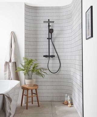 black and white bathroom with tiled shower area and a freestanding bath