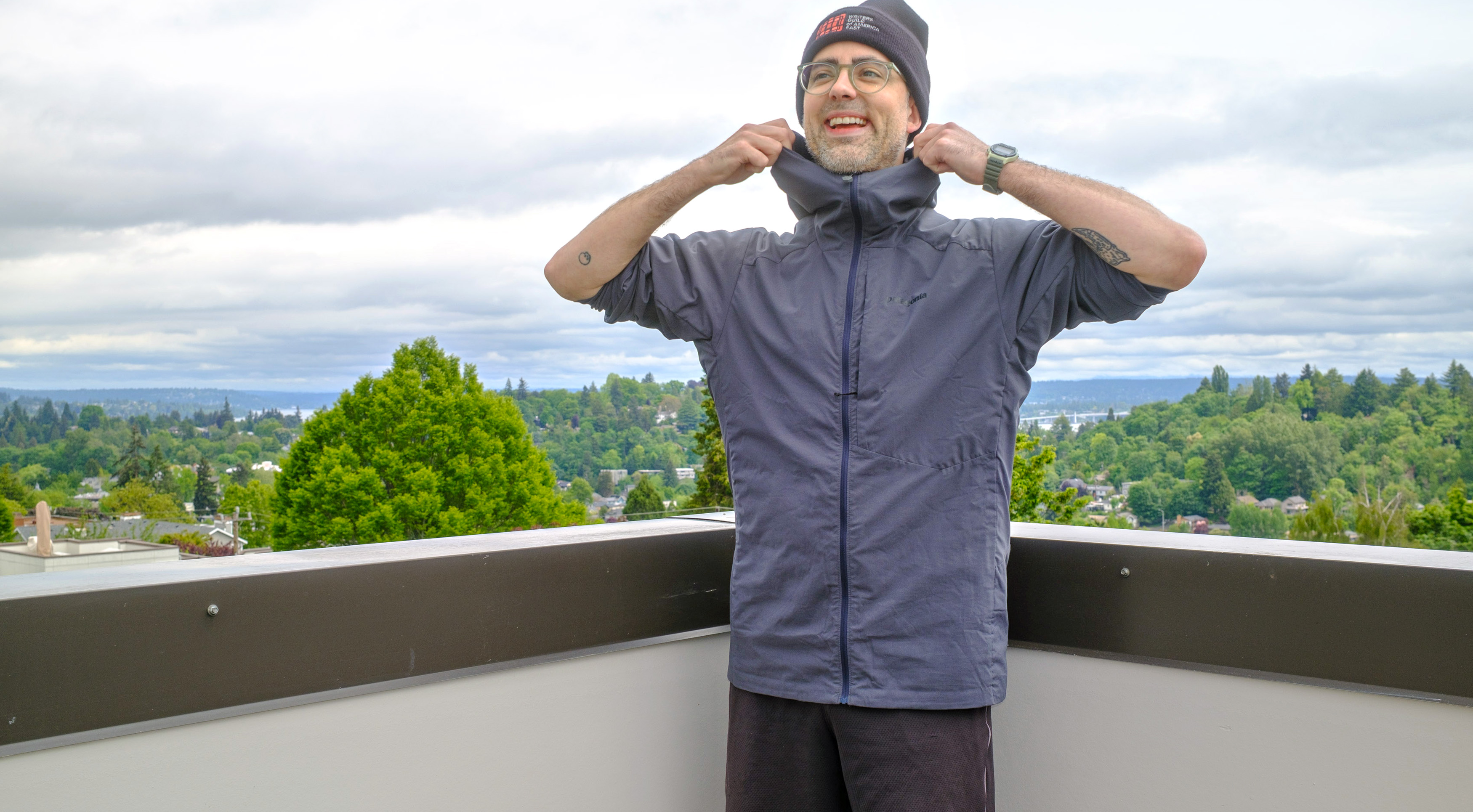 Senior writer Dan Bracaglia wearing the Patagonia Nano-Air Ultralight in grey/blue on the roof of his home in Seattle, Washington with trees and overcast skies in the distance