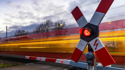 A train speeds through a railroad crossing so fast that it's just a blur.