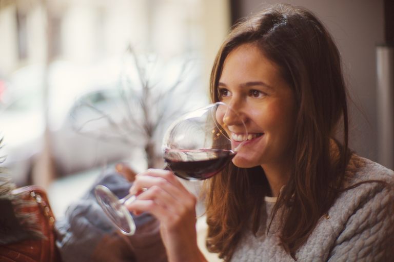 Beautiful happy lady drinking glass of red wine, wine hangover