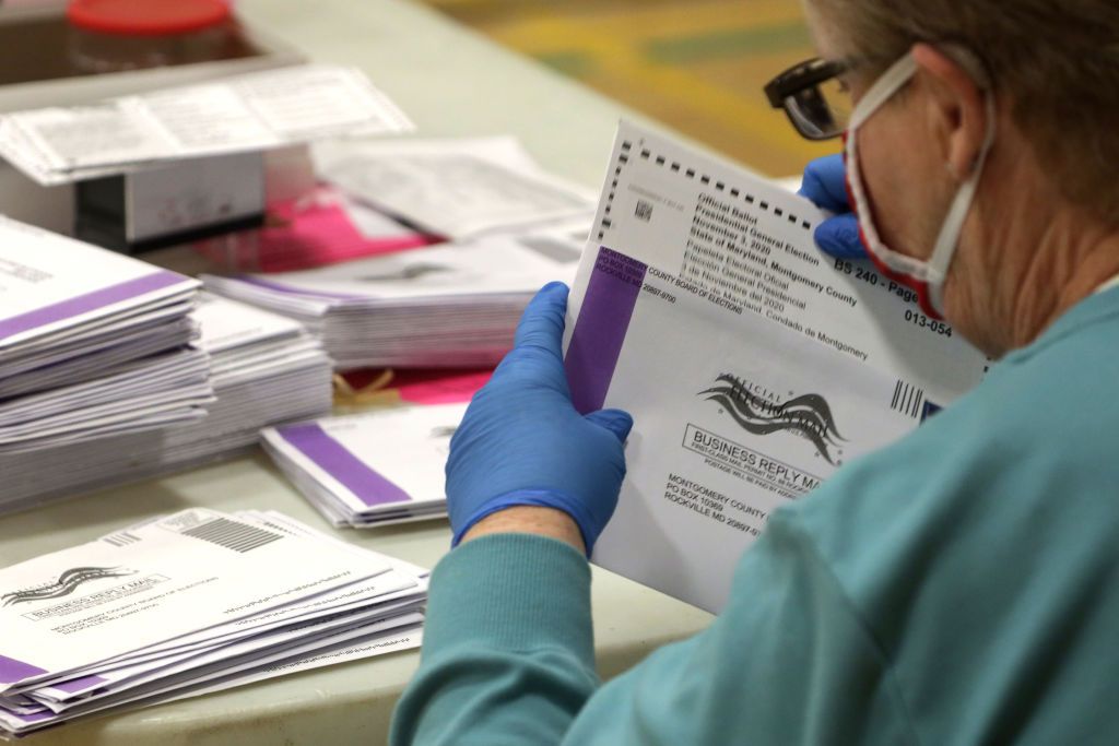 An election judge prepares early mail-in ballots to be scanned.